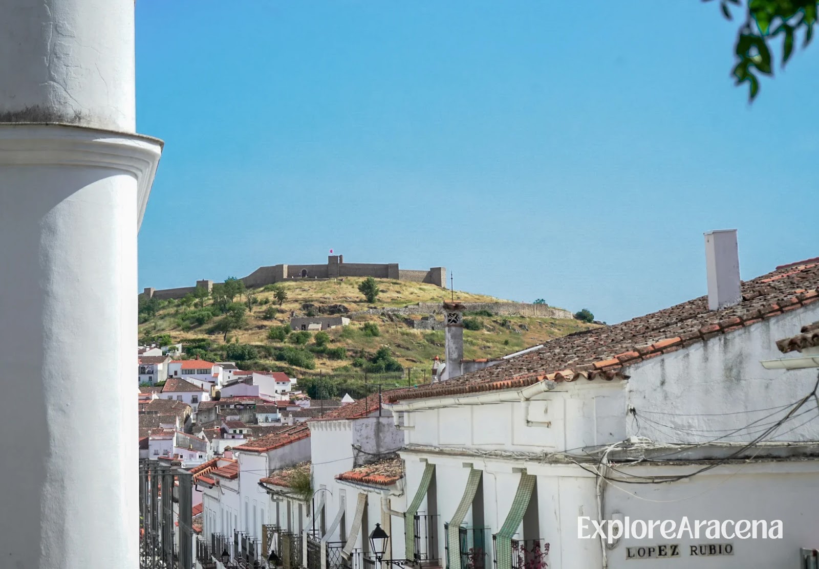 Aracena Castle overlooking the town’s whitewashed buildings beneath a clear blue sky.
