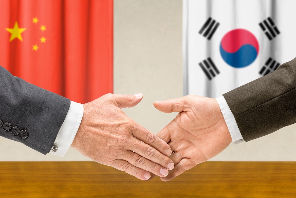 한국 발급 서류를 번역·아포스티유해 중국 제출용으로 준비하는 절차를 상징하는 중국·한국 국기와 악수