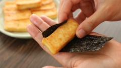 Đậu hũ trắng cắt miếng dài, dày khoảng 3cm. Chiên vàng giòn 2 mặt. Lá rong biển cắt miếng, quấn quanh thanh đậu.