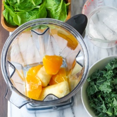 Lột vỏ chuối, cắt nhỏ rồi đông lạnh. Việc đông lạnh chuối sẽ giúp sinh tố sánh và mịn hơn. Gọt vỏ cam và thái cam thành múi, bỏ hạt nếu có. Rửa sạch cải xoăn và cải bó xôi. Cho chuối, cam vào máy xay sinh tố.