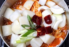 Cho khoai tây, hành tây, ớt đỏ khô và hành lá vào. Vừa đun vừa múc nước sốt trong nồi đổ lên trên thịt gà và khoai tây cho gia vị ngấm đều.