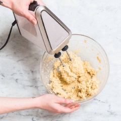 Bật trước lò nướng ở nhiệt độ 175°C/350°F. Lót giấy nến lên khay nướng và để riêng. Cho baking soda và bột mì vào tô, trộn đều. Cho bơ, tinh chất vani, đường trắng, đường nâu và muối vào một cái tô khác, trộn đều trong 5 phút, sau đó cho trứng gà vào đánh mịn.