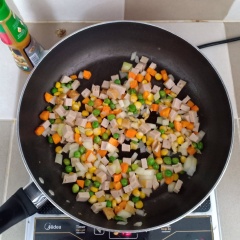 Làm nóng một chảo khác cùng 2 muỗng canh dầu, cho tỏi vào phi thơm, sau đó cho cà rốt và đậu hòa lan vào xào chín, tiếp đến cho hành tây và chả lụa vào xào cùng.