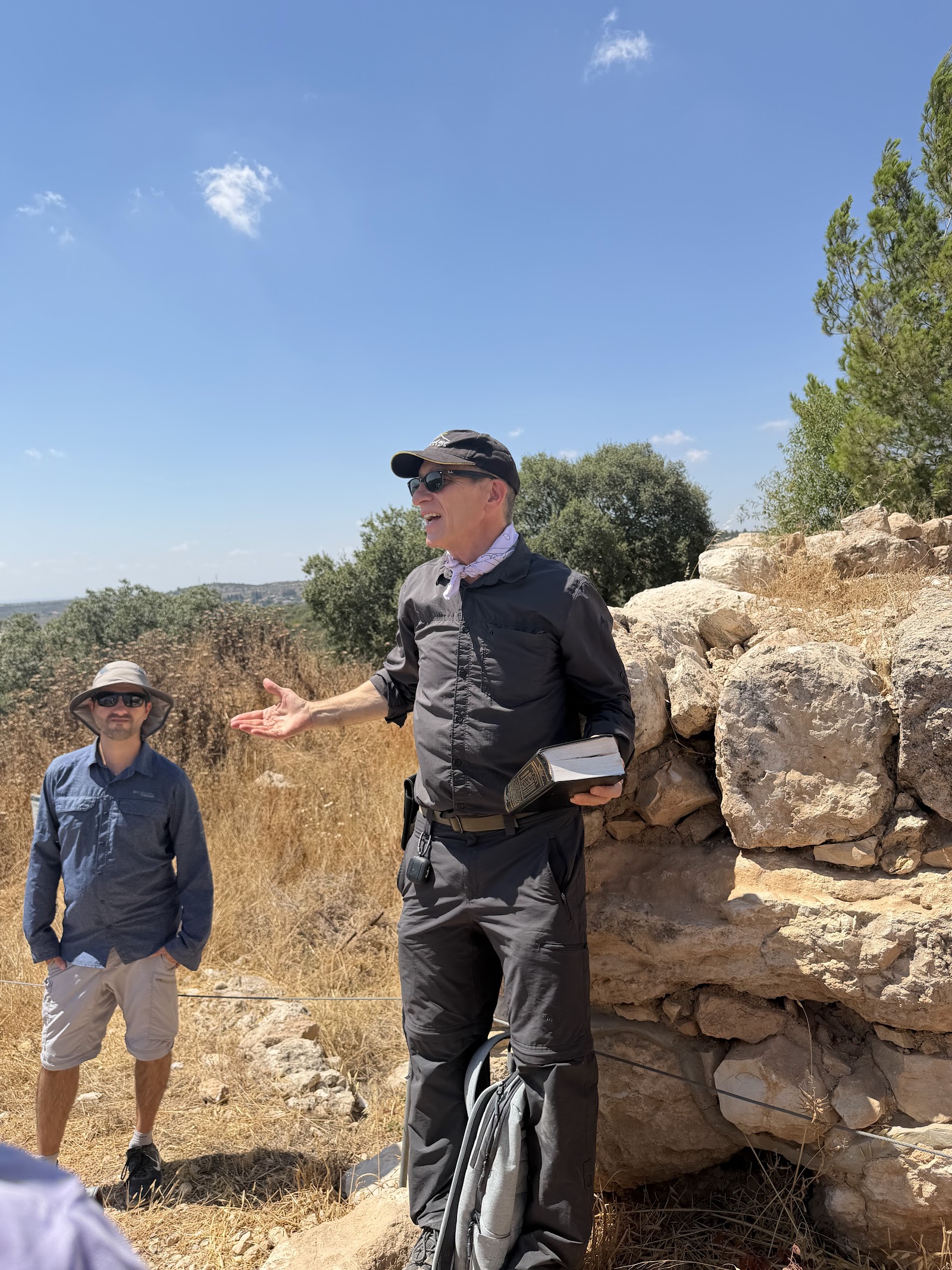 מדריך הטיול מספר על קרב דוד וגוליית עם ספר תנך ביד, על רקע עמק האלה