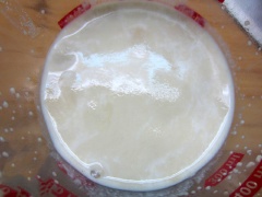 Làm ấm sữa (khoảng 35 - 40 độ C), cho 1 muỗng canh đường vào hòa đều rồi rắc men vào, đậy lại khoảng 5 phút cho men nở (men nở là sủi bọt như riêu cua). Trộn đều 250g bột mì với 1/2 muỗng cà phê muối, cho hỗn hợp sữa - men vào, dùng đũa cả khuấy đều rồi thêm 2 muỗng canh dầu ăn và thịt xông khói vào nhồi đều. Rắc ít bột áo ra bàn, nhồi theo kiểu gấp lại và ấn bằng gan bàn tay. Nhồi bột đến khi dai và không dính tay là được (khoảng 15 phút).