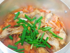 Cho cá vào nồi, nấu ở lửa vừa. Đến khi cá vừa săn mặt thì trở lại mặt kia của cá. Cho cà chua vào, cho thêm 1/2 chén nước lọc. Đun cá trên lửa nhỏ để cá thấm vị cà chua. Ớt cắt làm đôi, cho vào nồi cho thơm. Nấu đến khi cá chín, cá mềm thì cho hành lá cắt khúc vào. Hành chín, rắc thêm tiêu là hoàn thành.