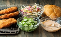 Chuẩn bị sẵn bánh mì kẹp và dưa leo để thưởng thức thôi nào! Đầu tiên, đặt miếng gà lên bánh mì, sau đó là salad, dưa leo rồi đến sốt mayonnaise.