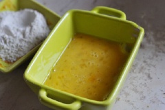 Cho vụn bánh mì vào khay nướng trong khoảng 5 phút, mở lò ở 180 độ C. Trộn vụn bánh mì đã nướng giòn với phô mai bào sợi. Trứng gà đánh tan.