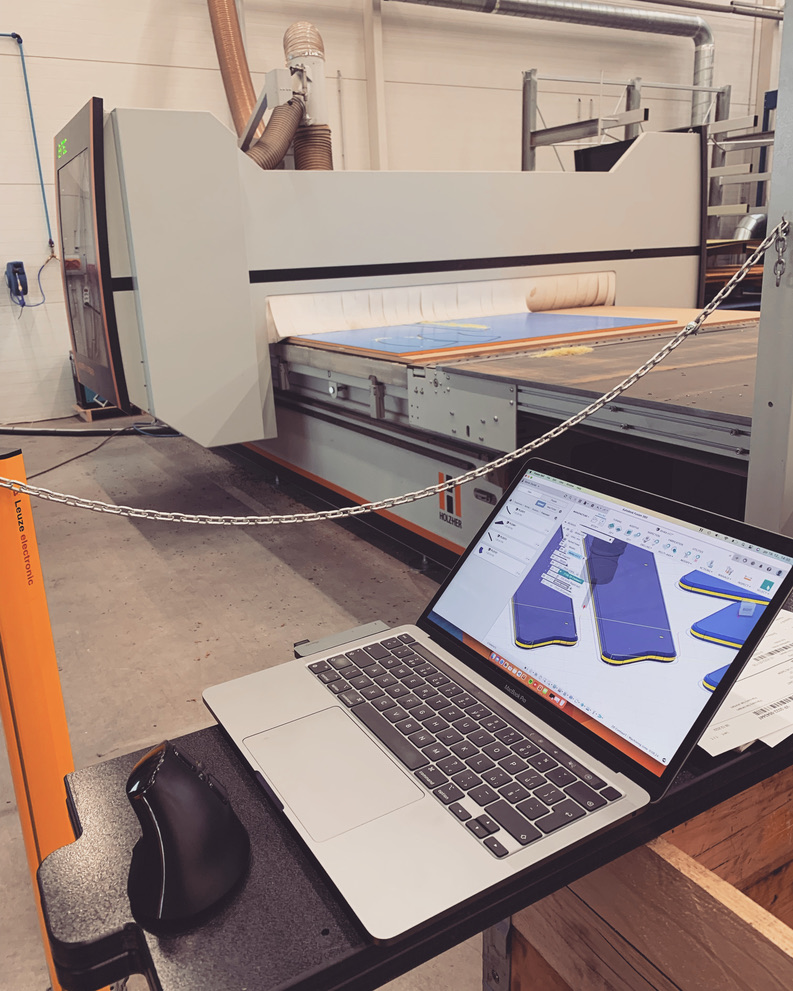 Fusion 360 open on laptop next to Holzher CNC machine on the shop floor
