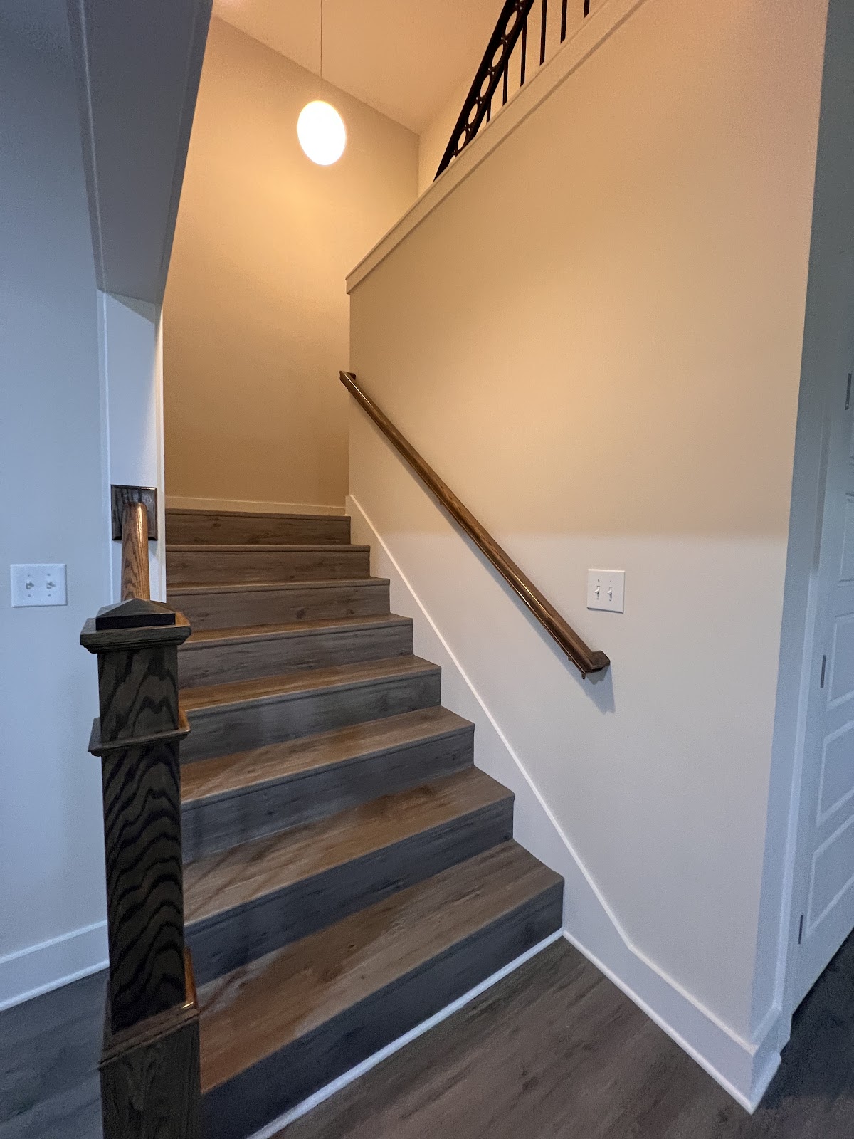 Interior staircase of the Inspiration Retreat project featuring dark wood-look treads, white risers, and a dark wood handrail.