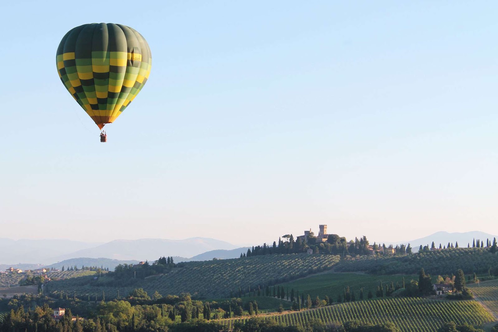 Hot-air balloon drifting above the rolling hills and countryside of Tuscany, Italy.