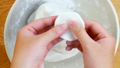 Ngắt bột thành những miếng nhỏ, vo tròn sau đó ấn dẹt và dàn bột ra thành những miếng bột mỏng. Đặt nhân đậu xanh vào giữa, gập đôi 2 mép bột lại và miết chặt cho dính vào nhau.
