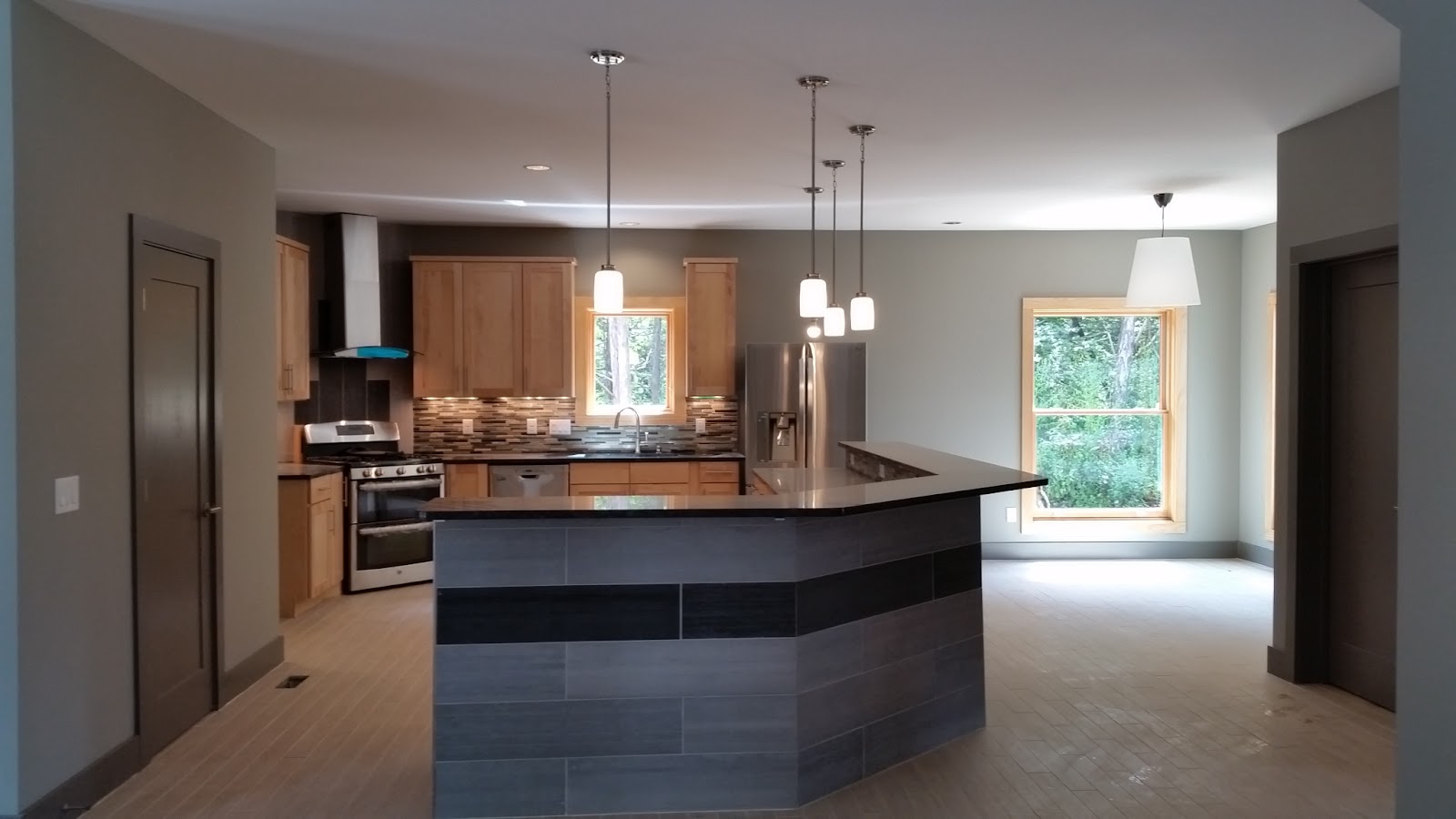 Interior view of a kitchen featuring a tiled island, wooden cabinetry, stainless steel appliances, and pendant lighting in a residential building in East Tennessee.