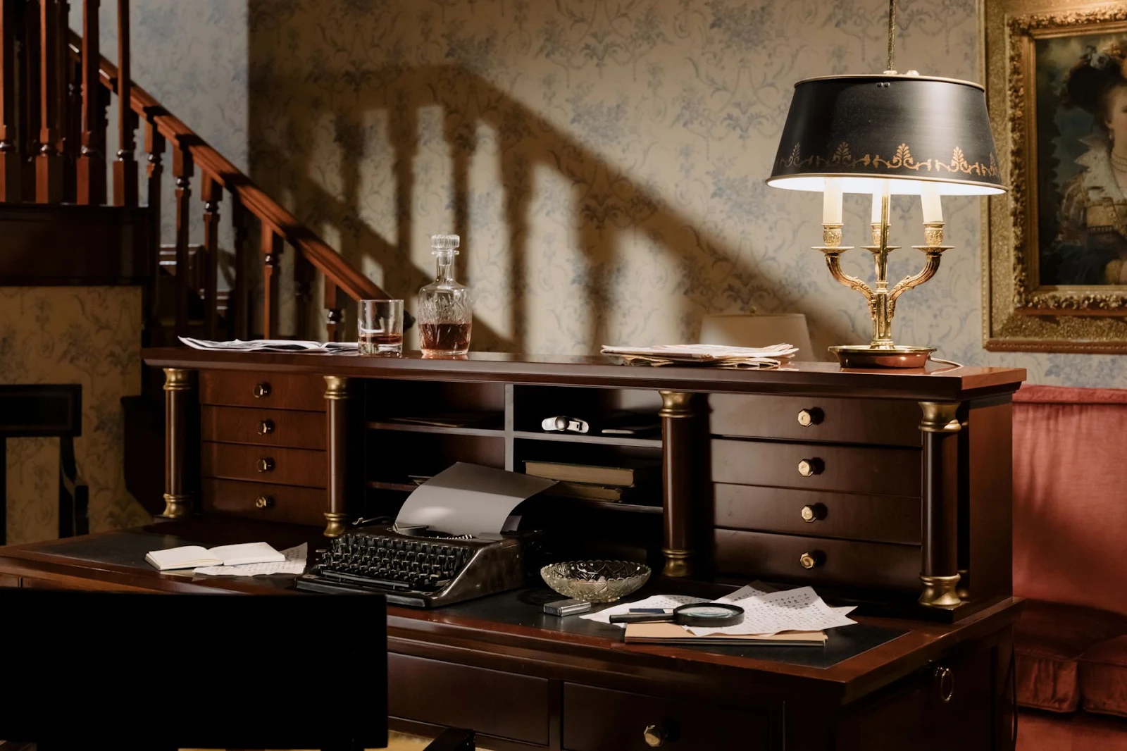 A vintage workspace featuring a classic wooden desk, typewriter, and elegant lamp in a retro interior.