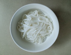 Lấy nồi khác cho nước vào đun sôi, nước sôi cho mì Udon vào chần cho mì rời nhau. Vớt mì ra cho vào các tô. Cho thêm cải thìa vào nồi nước dùng, nấu cho cải vừa chín tới để cải vẫn còn độ giòn.