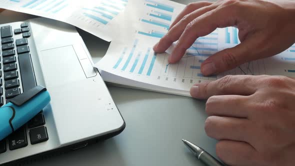 Analyzing Data Charts on Desk Next to Laptop Free Download – Envato Elements