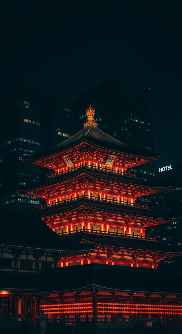 Dramatic Night View of a Traditional Singapore Buddhist Temple Against Modern City Skyline