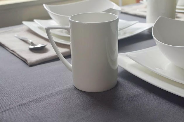 Gros plan d'une tasse du service de table 16 pièces en porcelaine tendre Red Vanilla Extreme sur une table avec une nappe grise