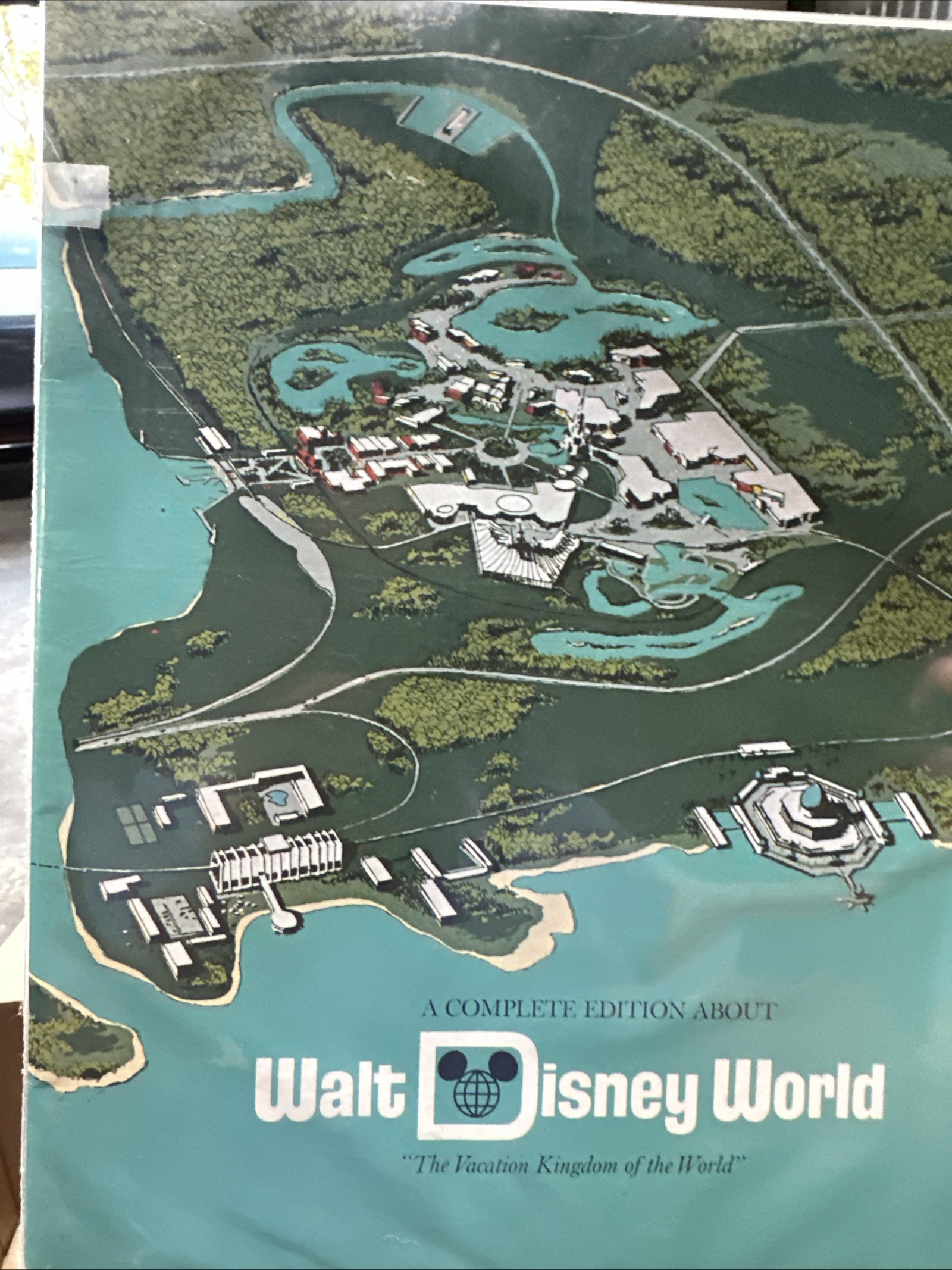 1971 Walt Disney World souvenir guidebook cover showing concept art rendering of Magic Kingdom, Seven Seas Lagoon, Contemporary Resort, and Polynesian Resort with the iconic Disney D logo