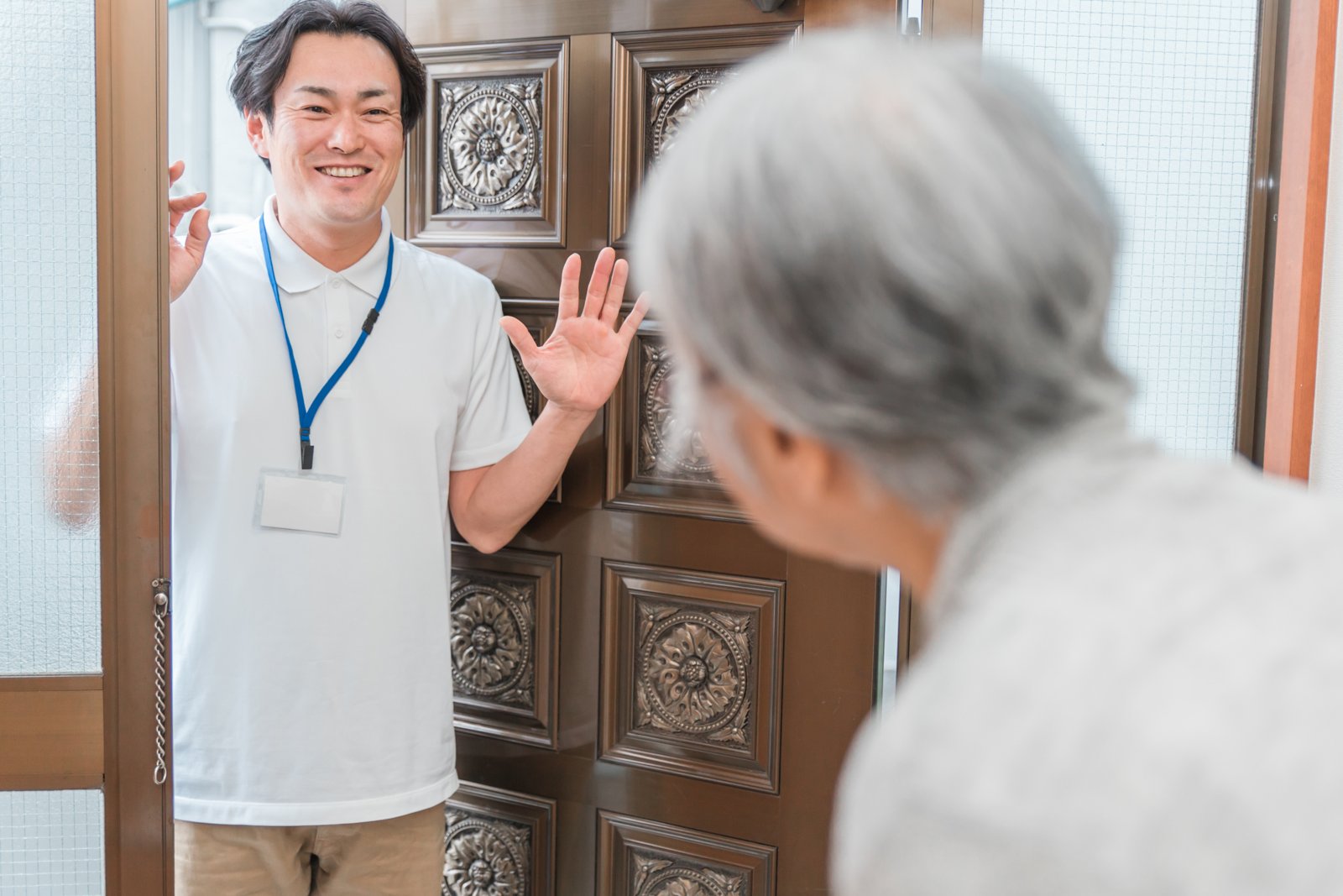 高齢者宅を訪問し玄関先であいさつする職員
