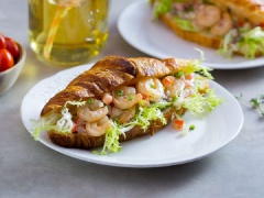 Bánh mì đem nướng cho giòn vỏ, hoặc nếu không có lò nướng bạn cũng có thể áp chảo bánh mì với chút dầu. Khi bánh mì đã giòn, dùng mũi dao rạch bánh mì làm đôi, xếp rau diếp thành lớp mỏng bên trong, kế đó mới múc phần salad tôm vào xếp đầy ruột bánh. Nếu ăn cay, bạn có thể thêm tương ớt hoặc ớt thái miếng vào tùy khẩu vị.