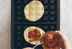 Làm nóng máy nướng bánh waffle, quét một lớp dầu mỏng rồi trải 2 miếng bột bánh lên, cho lần lượt ít sốt cà chua, phô mai, lá húng quế, sốt pesto lên, dùng 2 miếng bánh khác đậy lại. Gập máy xuống và nướng trong khoảng 3-4 phút hoặc đến khi bánh chín vàng.