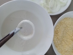 Rắc một ít bột mì khô áo mỏng những khoanh hành. Sau đó nhúng vào bột mì pha, gắp hành lên cho bột chảy bớt rồi lăn vào bột xù. Phủ đều khoanh hành nhé.