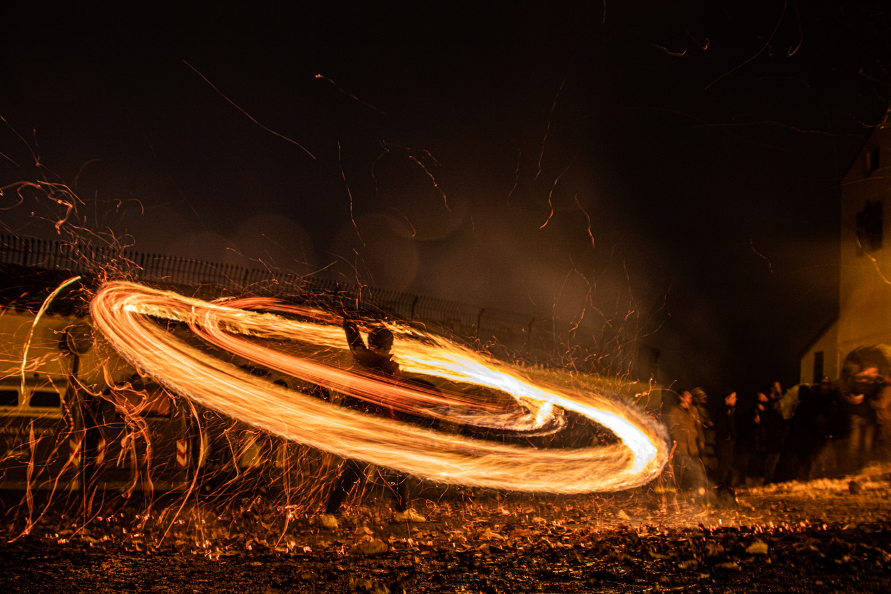 Two circles of fire created by burning rehiletes being spun at night in Aracena.