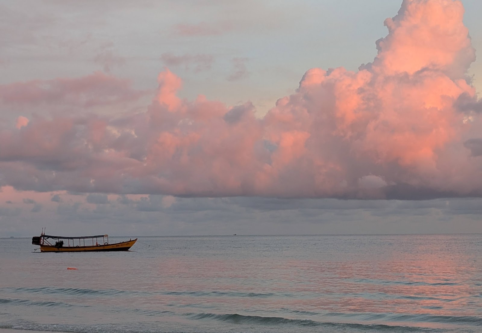 Pink and purple fluffy clouds reflected on still water, empty
                 except for a small boat in the midground