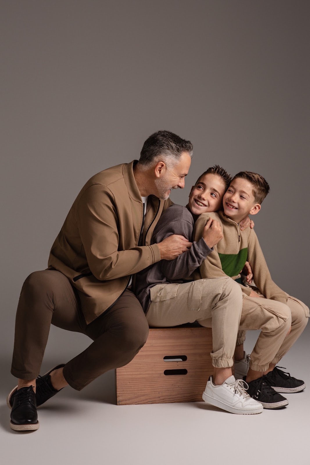 Pai abra�ando os dois filhos em retrato afetivo para campanha de Dia dos Pais da JCanedo.