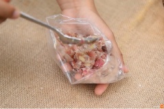 Tiếp theo, cho thịt heo bằm, da heo, tỏi giã nhuyễn, cơm nếp, 2 muỗng canh muối vào một cái túi nilon, bóp nhẹ hỗn hợp trên cho quyện vào nhau. Chia hỗn hợp nem thành những miếng nhỏ vừa ăn, cuốn từng miếng nem bằng giấy bóng, gói thật chặt rồi cố định lại bằng dây chun. Ở bước này nếu bạn muốn nem có vị cay thì có thể cho ớt thái nhỏ vào cùng. Mang nem đi để ở nơi thoáng mát và khô ráo, không có ánh nắng mặt trời để tránh trường hợp nem bị lên men dẫn đến quá chua. Để yên khoảng 3 ngày.