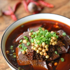 Bày trí huyết heo chua nóng: Cho huyết heo ra tô, dội chén sốt vừa pha lên trên, rưới thêm ít nước dùng đã đun, nêm nếm cho vừa miệng. Thêm ít sốt ớt đậu cay, đậu nành chiên và hành lá, dùng nóng.