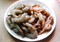 Mực sơ chế, bóc màng, bỏ mai và túi mực, bóp sạch với muối và giấm. Thái ngang con mực thành nhiều miếng hình vành khuyên. Tôm bóc vỏ giữ lại phần đuôi, bỏ chỉ đen ở lưng. Cho tôm và mực chung vào 1 tô lớn, ướp với 2 muỗng canh rượu trắng và 1/2 muỗng cà phê muối tiêu trong khoảng 15 phút cho ngấm. Lấy 1 túi nilon kéo miệng, cho nửa chén bột chiên vào rồi đổ tôm và mực vào túi bột, kéo miệng túi lại, xóc đều cho bột bao hết lấy tôm và mực.