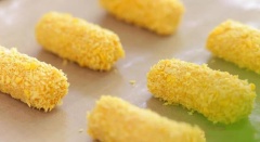 Tiếp đến, cho 15g bột yến mạch vào tô khoai lang nghiền trộn cho quyện đều. Múc 1 ít hỗn hợp khoai lang, ấn dài và dẹp, sau đó đặt que nhỏ phô mai vào bọc kín lại trông như viên chả giò. Lăn các viên bánh qua phủ 1 lớp bột chiên xù.