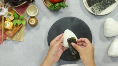 Dùng tay tạo hình cơm theo sở thích nha. Cuối cùng gỡ màng bọc thực phẩm ra và cho thêm 1 lá rong biển vào.