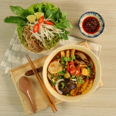 Cho bún ra tô, cho phần topping lên trên, rắc thêm ngò gai và hành tây lên mặt, sau đó chan phần nước lèo lên là hoàn tất. Món ăn dùng kèm với ớt xắt lát, chanh và rau sống.