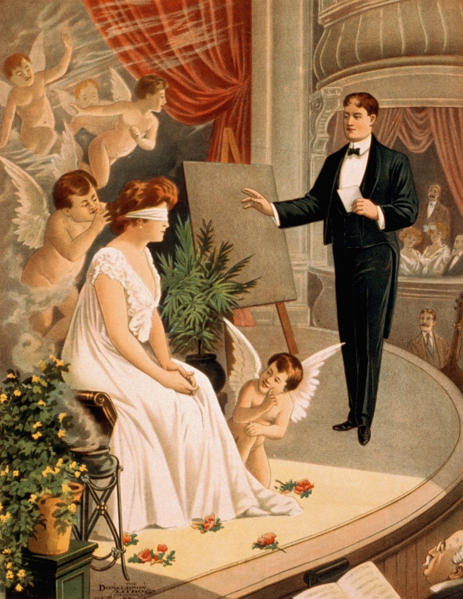 Hypnotist and blindfolded woman with angels on stage 1900