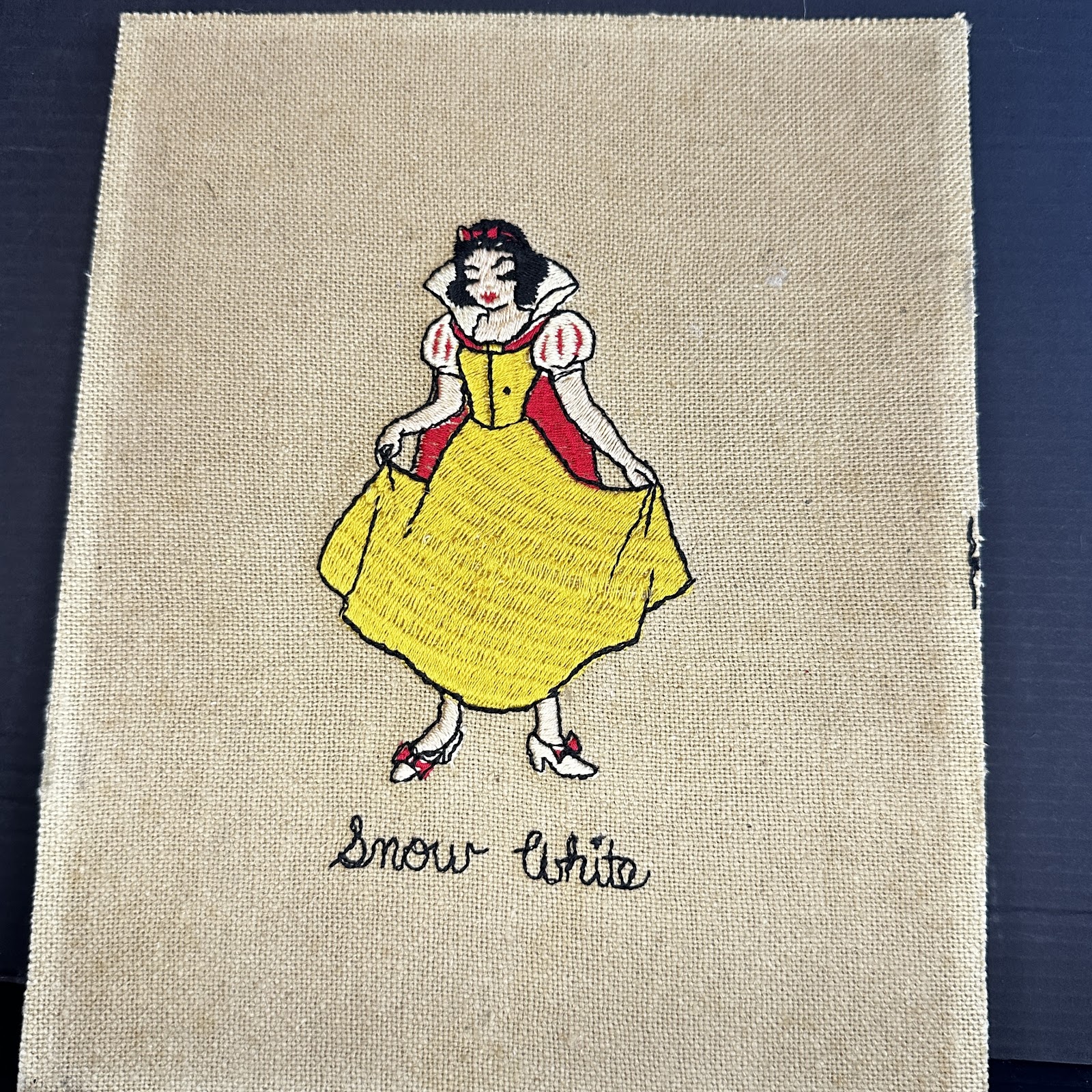 Hand-embroidered fabric panel depicting Snow White in her classic blue and yellow dress, mid-century needlework in very good condition