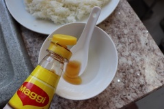 Cơm trắng nóng múc ra dĩa để dễ trộn hơn, bạn cũng có thể bỏ vào tô. Pha nước trộn cơm: cho giấm vào chén cùng 1 xíu muối rồi trộn đều cùng dầu mè, nước tương và đường.