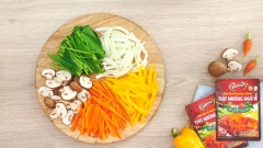 90gr nấm mỡ nâu rửa sạch, cắt đôi. 90gr ớt chuông vàng bỏ cuống bỏ hạt thái sợi. 90gr hành tây lột vỏ, thái sợi. 90gr Cà rốt gọt vỏ thái sợi. 90gr Cải bó xôi rửa sạch cắt khúc ngắn. Đun 1 nồi nước sôi, cho các loại rau củ vào trụng nhanh cho mềm, sau đó cho vào nước lạnh. Đun 1 nồi nước sôi khác, cho 160gr miến khô vào trụng 3 phút cho chín mềm.