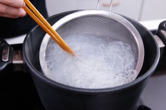 Đun sôi một nồi nước, cho miến vào trụng sơ cho đến khi miến mềm và trong hơn thì vớt ra bát nước lạnh. Gắp miến ra cho ráo. Làm nóng chảo với 1 muỗng canh dầu. Cho hành, tỏi và sả vào xào thơm.