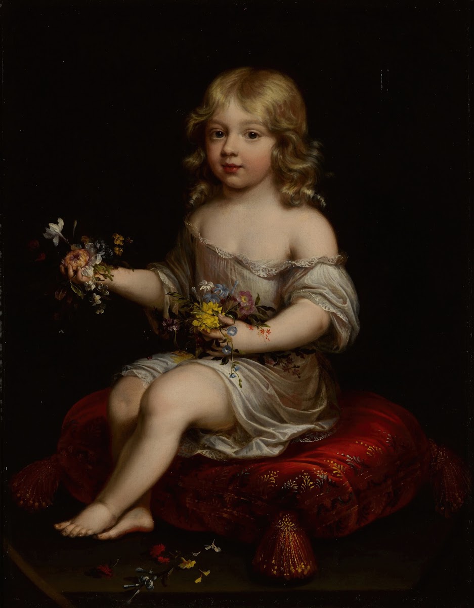 Portrait of a young boy seated on a cushion holding flowers