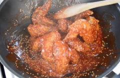 Bây giờ là lúc để làm nước sốt, thêm 5 muỗng canh tương cà chua, 3 muỗng canh tương ớt, 3 muỗng canh đường, 1/2 muỗng cà phê muối, 1/4 muỗng cà phê tiêu và 60ml nước vào chảo và đun nóng trên lửa cao trong khi khuấy. Khi nước sốt bắt đầu sôi bong bóng, thêm vào cánh gà đã chiên và trộn nhanh để nước sốt bao phủ cánh. Sau đó, thêm vào 2 muỗng canh hạt mè và trộn với gà. Cuối cùng chỉ rắc 2 muỗng canh hành lá cắt nhỏ, trộn lần cuối là được.