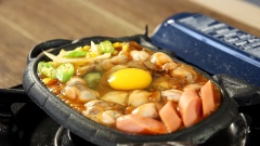 Bắc chảo gang lên bếp cho nóng, cho vào 20gr bơ thực vật rồi đảo đều, cho vào 30gr hành tây, 30gr bắp Mỹ, 20gr đậu bắp. Đảo đều. Sau đó cho xúc xích, hàu lên trên mặt. Đập 1 quả trứng gà vào. Để khoảng 1 phút, cuối cùng rắc phô mai vào đến khi phô mai tan chảy hết thì tắt bếp. Rắc tiêu và trang trí ngò rí trên mặt.
