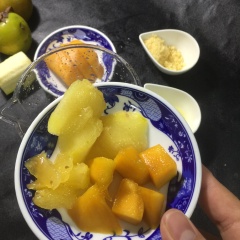 Xoài hồng cắt miếng cho vào cối xay. Thêm chuối vào cùng nước cam.