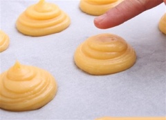 Dùng màng bọc thực phẩm bọc kín bột lại rồi để bột nghỉ trong khoảng 30 phút. Tiếp theo, bạn cho bột vào túi bắt bông kem, lắp đui rồi bắt thành nhiều chiếc bánh có đường kính khoảng 2cm. Dùng tay ấn chỏm nhọn xuống, đồng thời xịt một ít nước lên hỗn hợp bột.