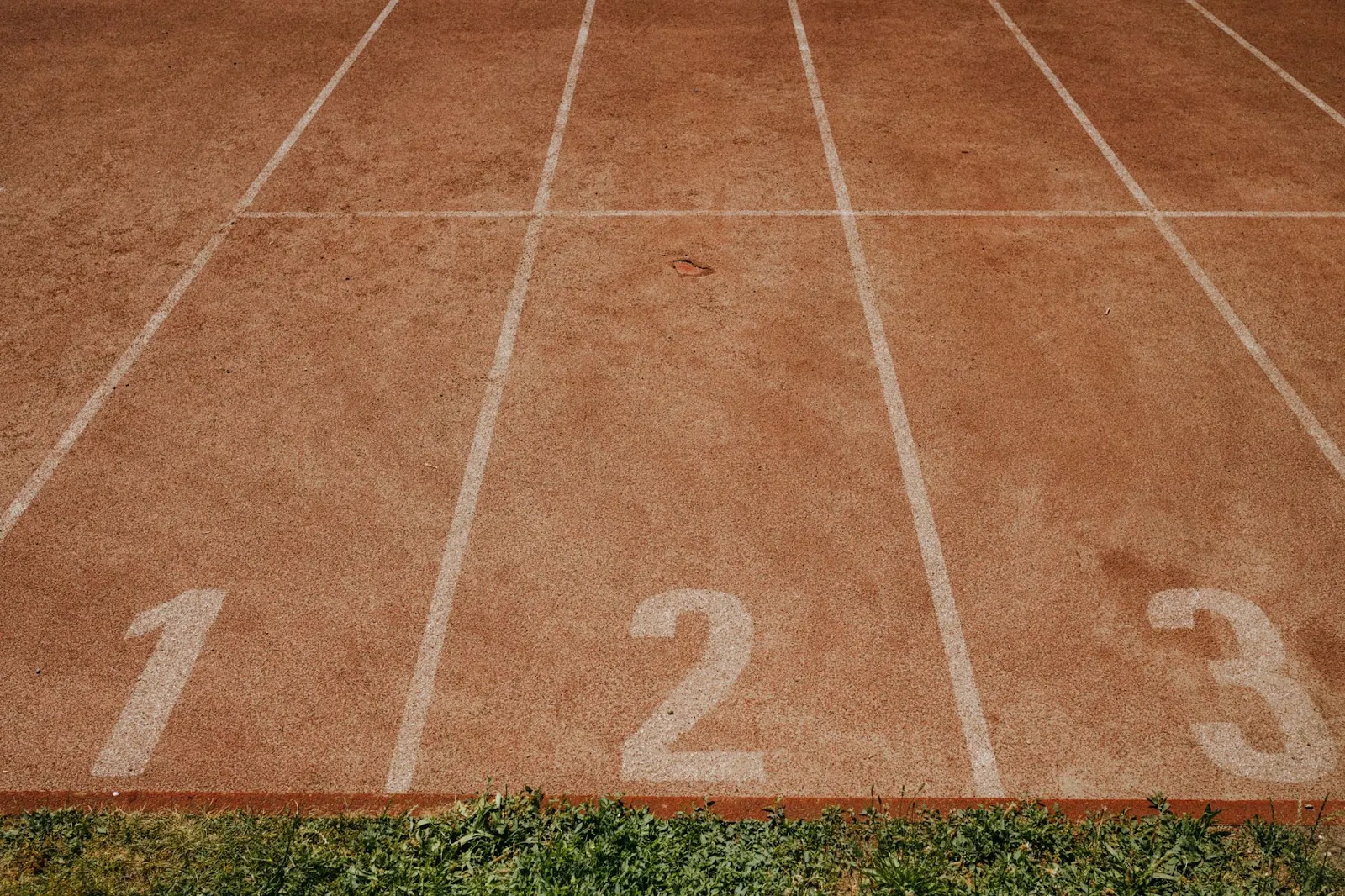 Top view of an athletics track featuring lanes marked with numbers 1, 2, and 3.