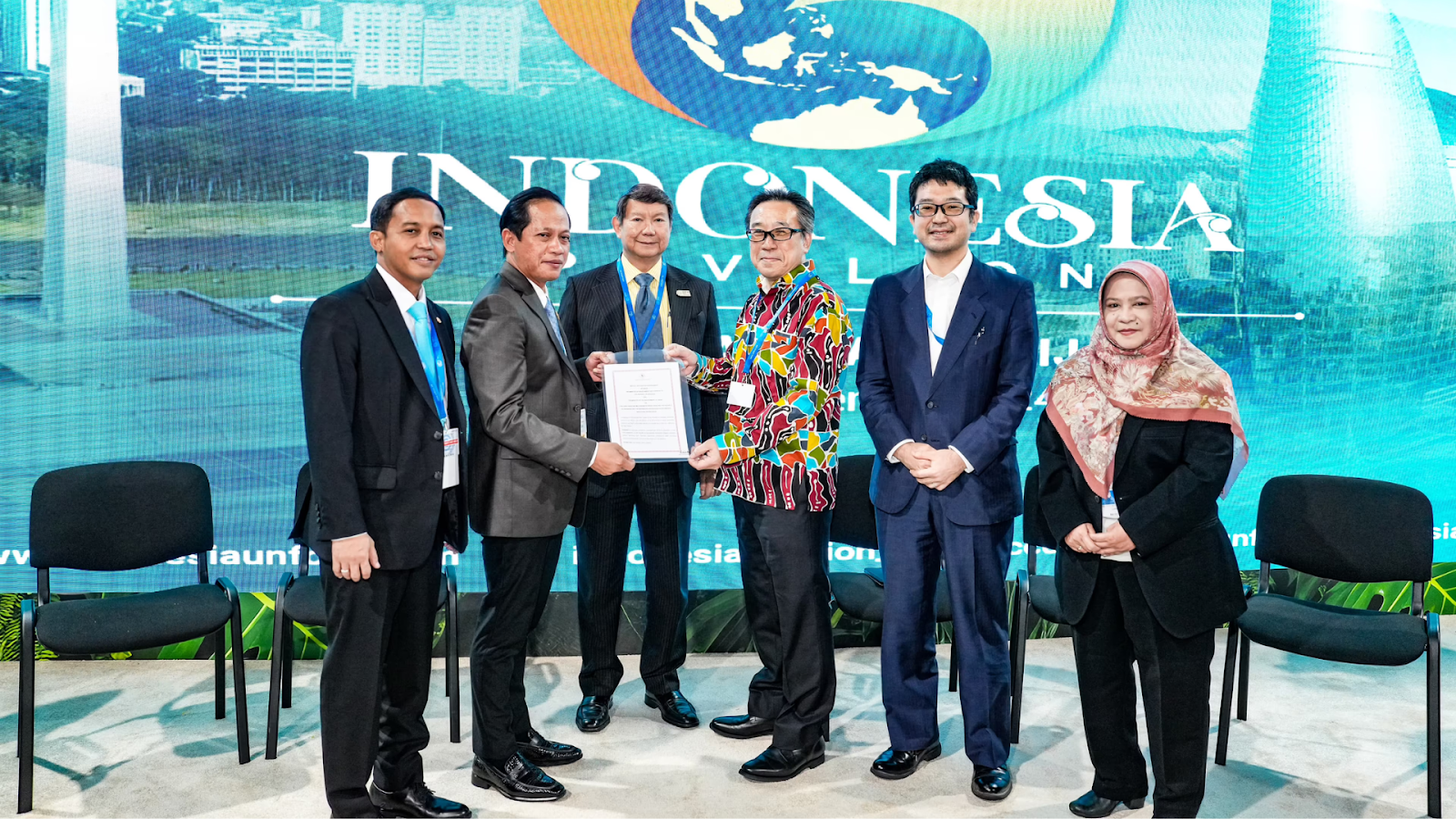 Indonesia and Japan representatives exchange documents during a signing ceremony for a bilateral carbon trading agreement at COP29.