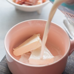 Cho 2 miếng phô mai con bò cười vào chén cùng với 300ml sữa tươi, dùng muỗng khuấy, tán phô mai cho hòa huyện với sữa.