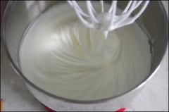 Thêm vào 80g đường rồi dùng máy đánh đến khi lòng trắng đông cứng lại, hỗn hợp tăng thể tích gấp 3 lần. Hỗn hợp đạt là lúc bạn nhấc que lên, lòng trắng dính trên que cứng theo hình chóp hơi ngoặc xuống.